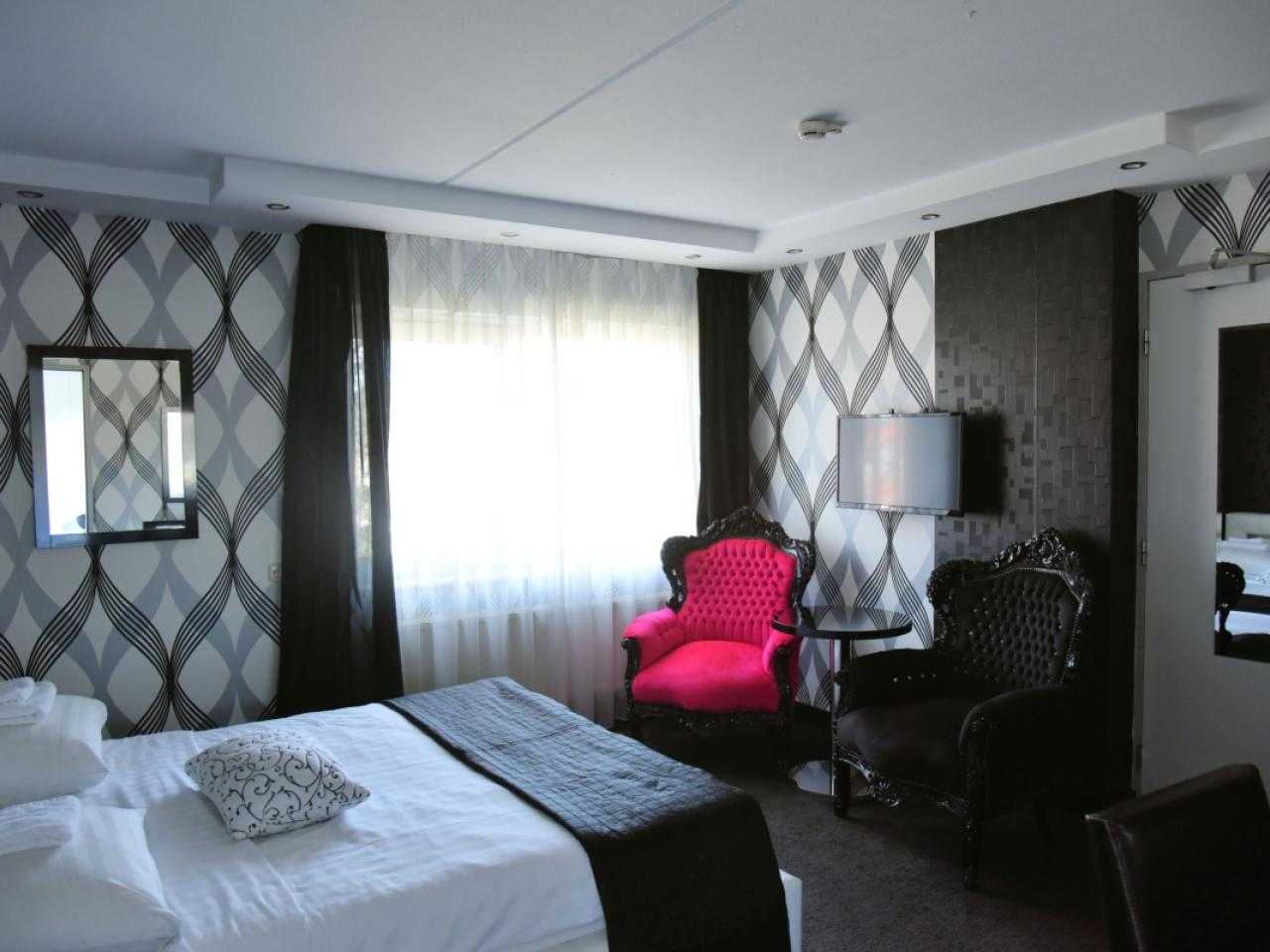 Interieur hotelkamer hotel Zwanenburg met rode stoel in de hoek